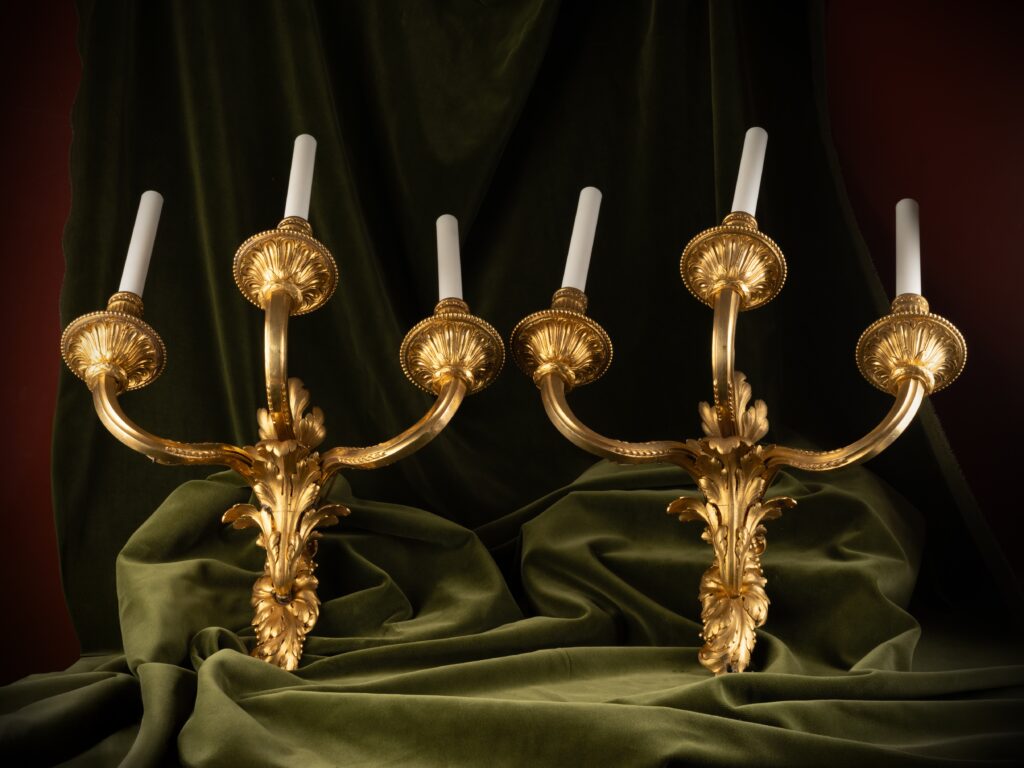 Set of four three-light wall sconces in gilt bronze