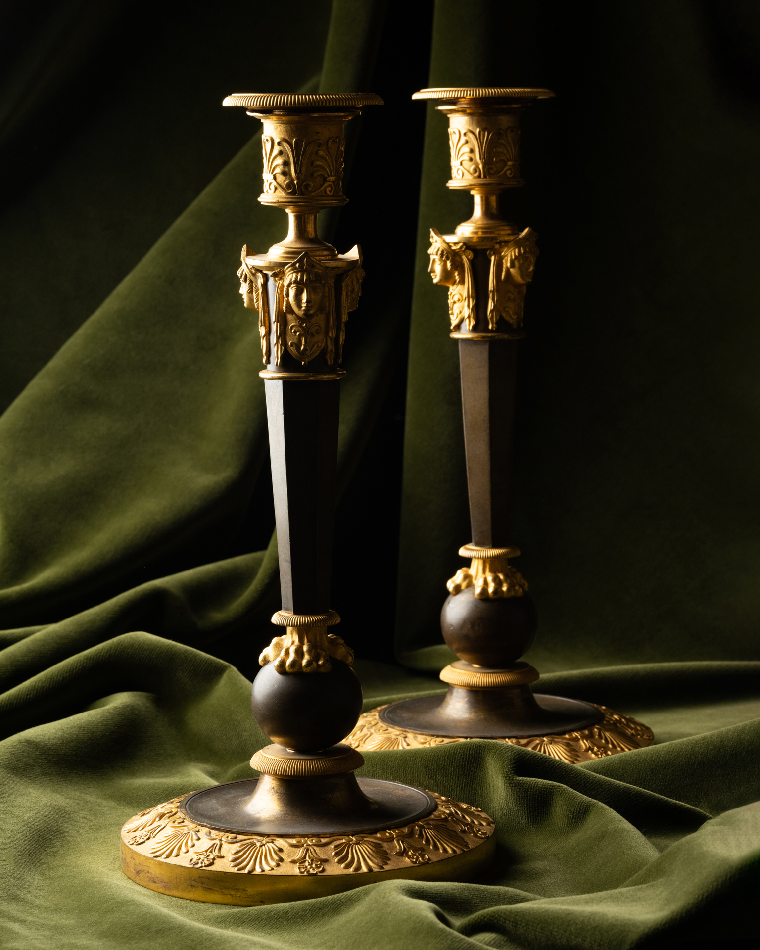 A Set of Four Empire Parcel-Gilt “Claw-Foot” Candlesticks with Antique Masks, attributed to Claude Galle