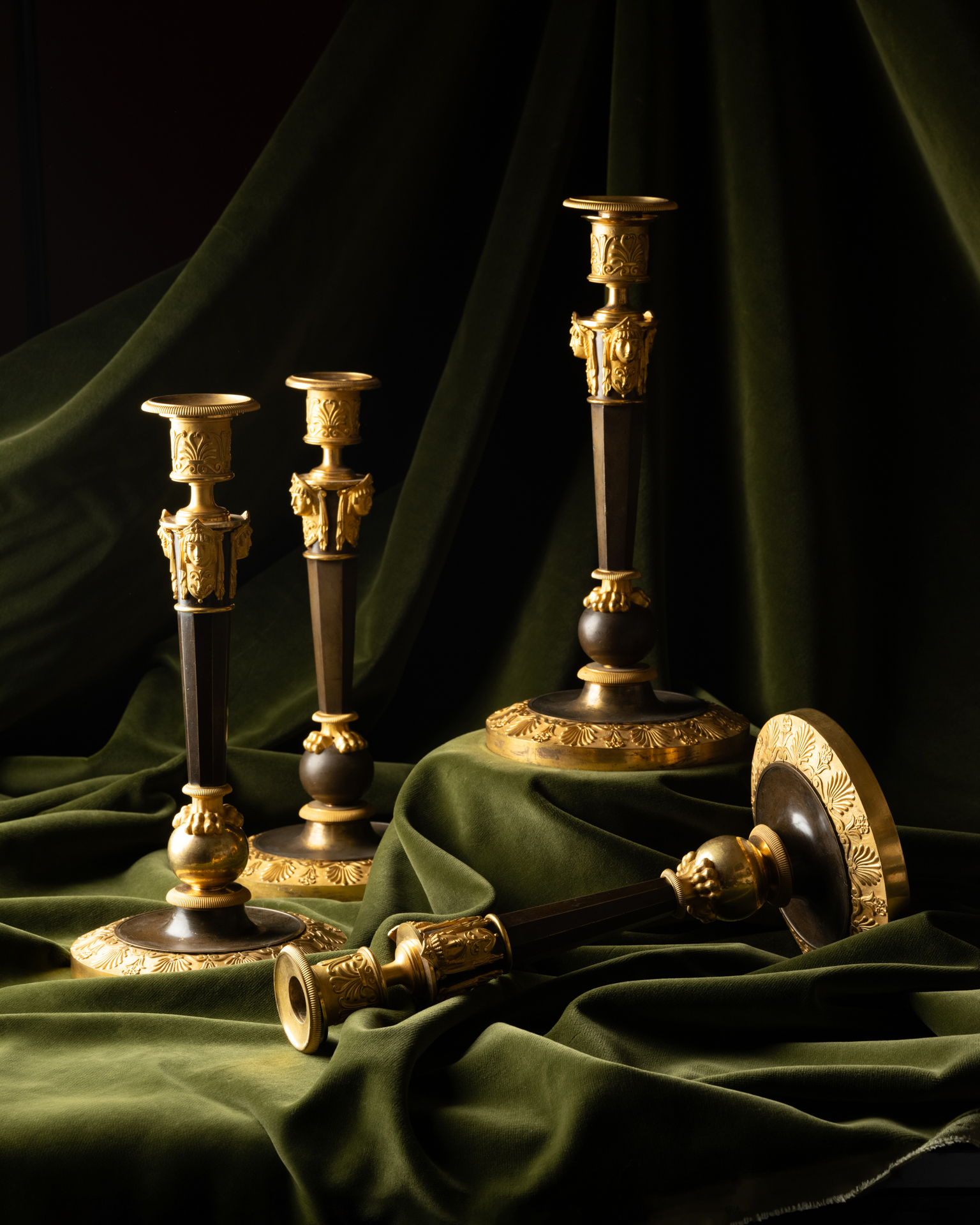 A Set of Four Empire Parcel-Gilt “Claw-Foot” Candlesticks with Antique Masks, attributed to Claude Galle