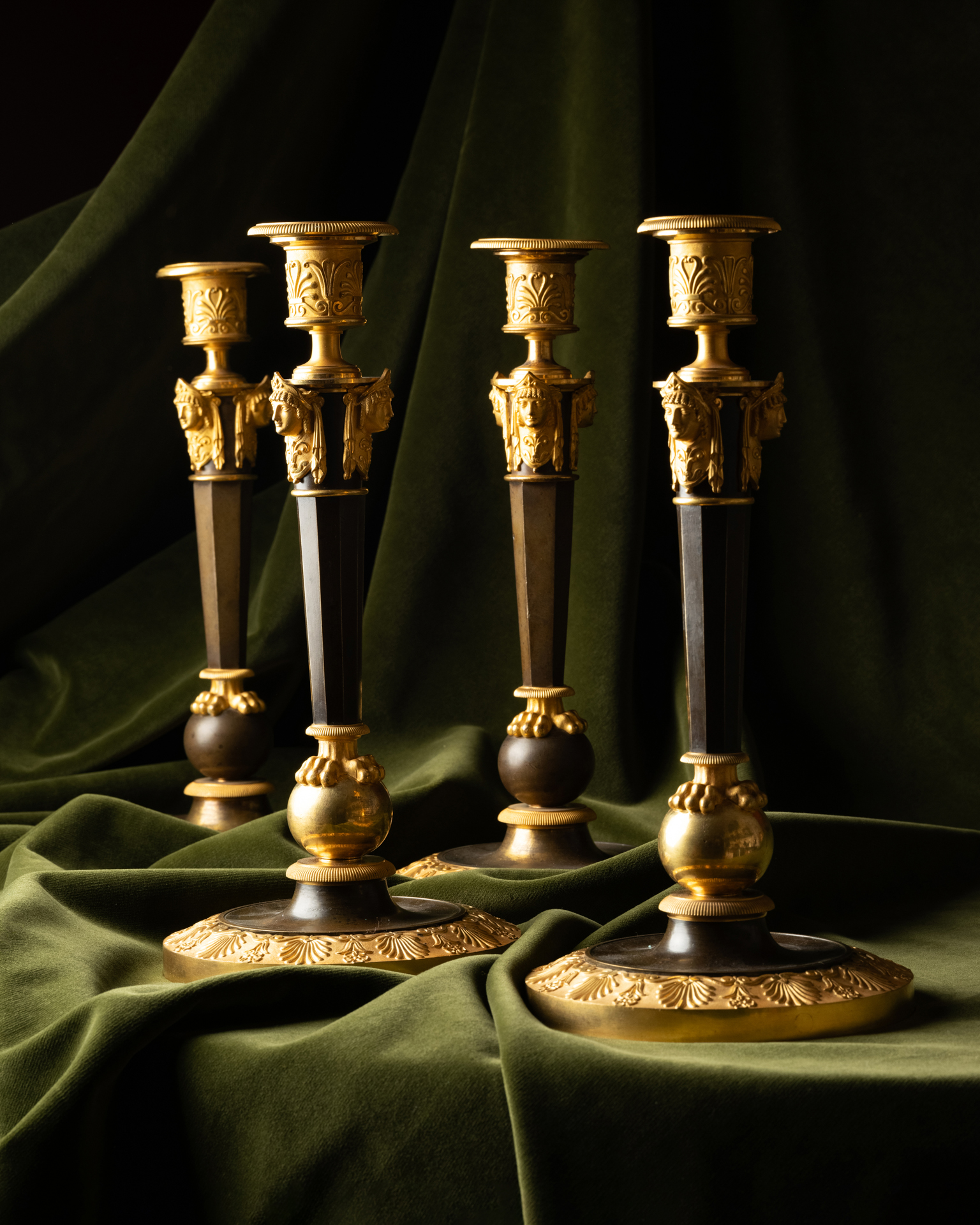 A Set of Four Empire Parcel-Gilt “Claw-Foot” Candlesticks with Antique Masks, attributed to Claude Galle